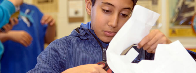 Male student cutting paper